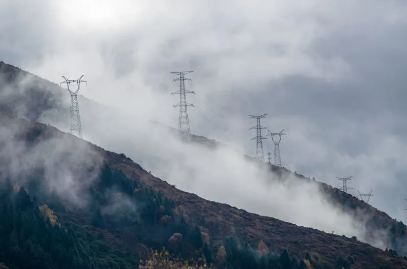 Power lines and pylons over a mountainside in fog
