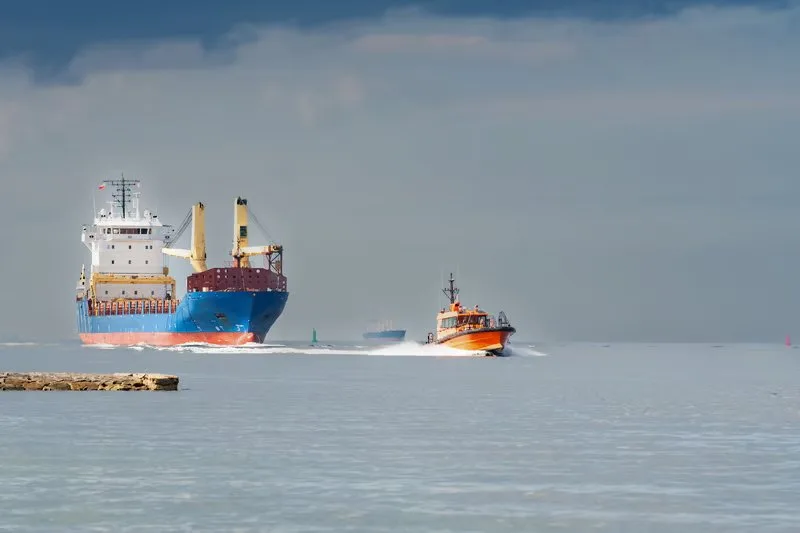 Cargo ship and pilot boat at the entrance to a harbour