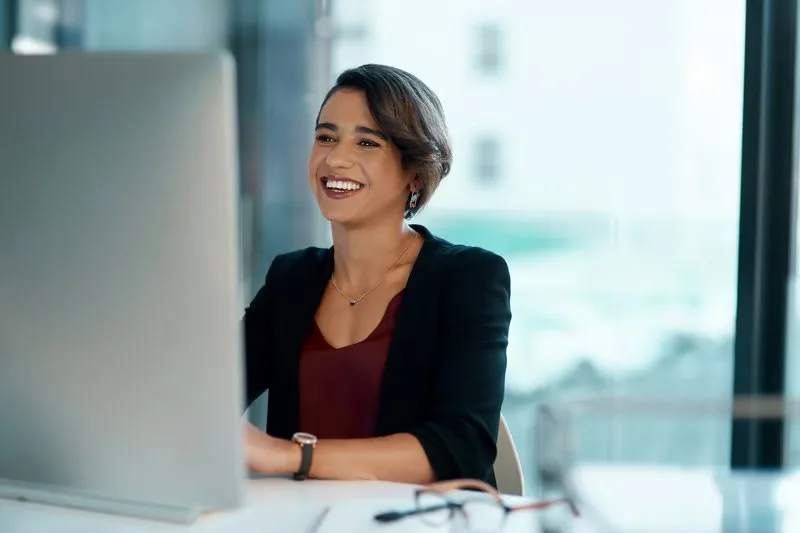 Smiling woman working at a computer in a bright office