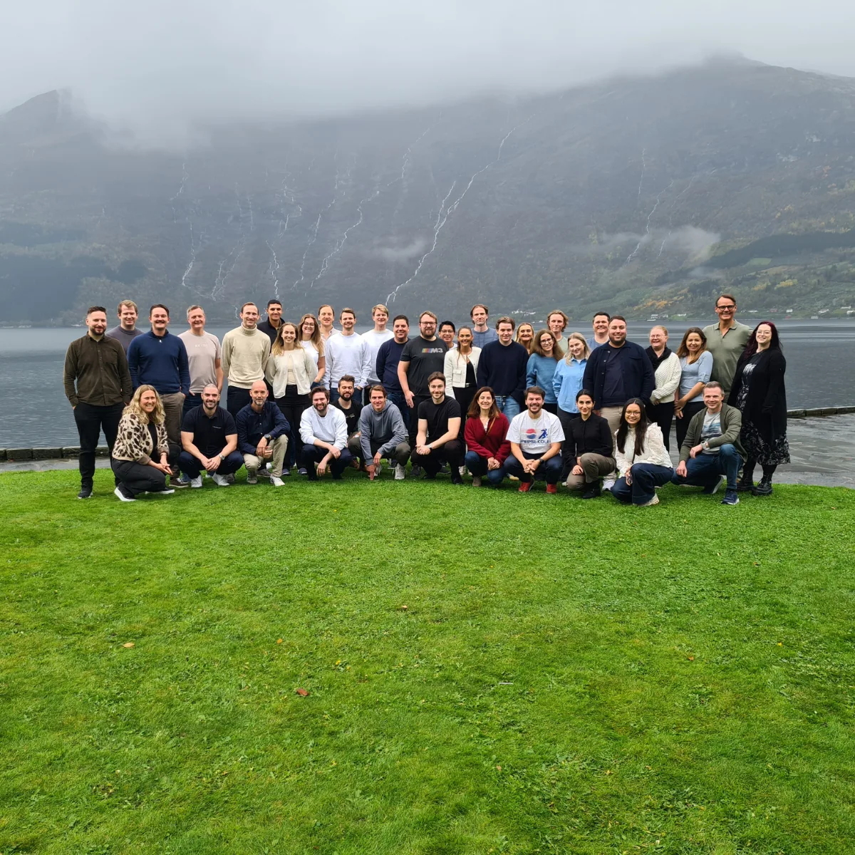 The team gathered outdoors in front of a fjord and mountains