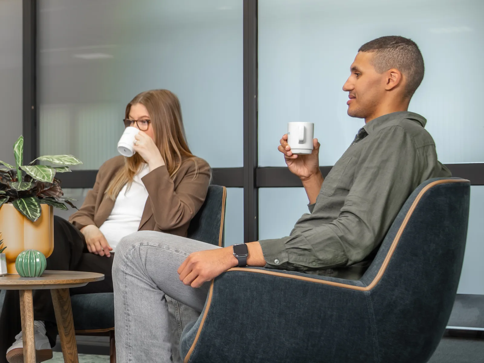 To kolleger med kaffekopper i samtale i et kontorlandskap